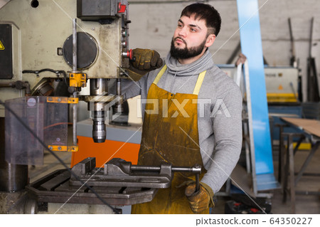 Man mechanic using drilling machine in workshop Man mechanic using drilling machine in workshop 64350227