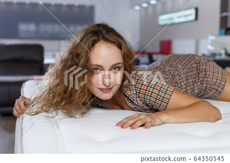 Young woman lying and testing mattress Young woman lying and testing mattress 64350545