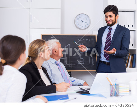 Manager male is reading financial report to colleagues on meeting Manager male is reading financial report to colleagues on meeting 64350554