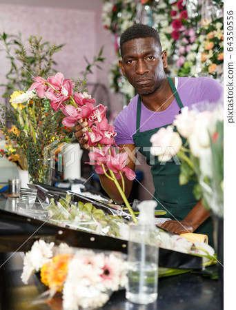 Man creating floral arrangement with orchids Man creating floral arrangement with orchids 64350556
