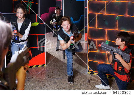 Fine teens aiming laser guns at other players Fine teens aiming laser guns at other players 64350563