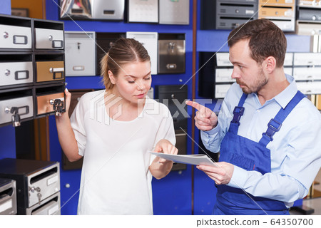 Male seller helping young client woman choosing new mailbox 64350700