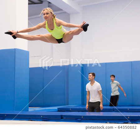 Woman jumping in trampoline center Woman jumping in trampoline center 64350882