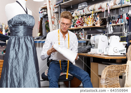 Fashion designer standing near tailor mannequin 64350994