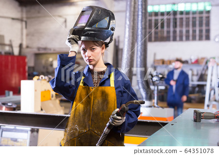 Young woman using welder for construction work 64351078