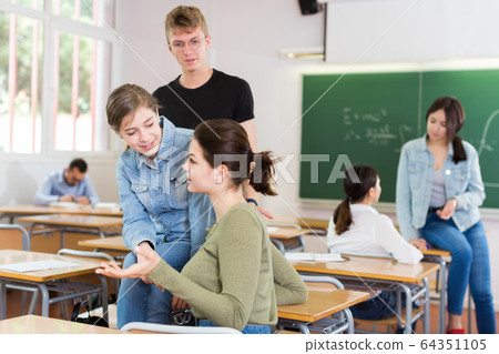 Two girl and boy are sitting at the desk and talking about life Two girl and boy are sitting at the desk and talking about life 64351105