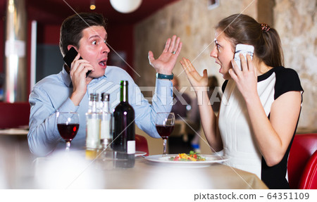 Couple with phones at restaurant Couple with phones at restaurant 64351109