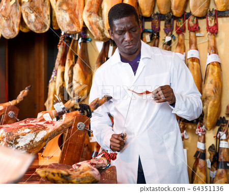 Butcher shop owner checking quality of jamon 64351136