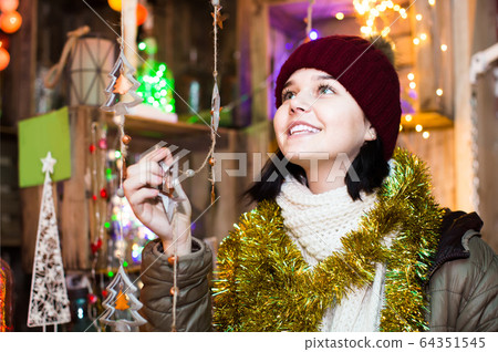 girl choosing Christmas decoration at market girl choosing Christmas decoration at market 64351545