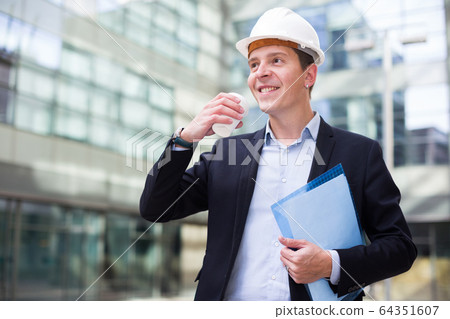 Professional man in helmet working with documents Professional man in helmet working with documents 64351607