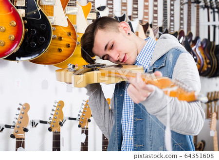 Male is choosing best electric guitar Male is choosing best electric guitar 64351608