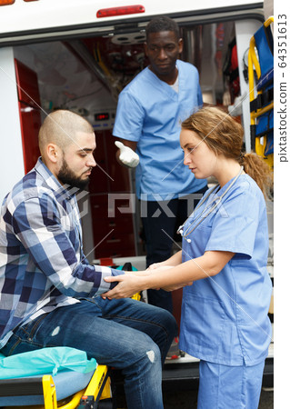 Paramedic team providing first aid to man Paramedic team providing first aid to man 64351613
