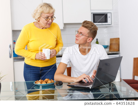 Woman taking care of adult son at kitchen Woman taking care of adult son at kitchen 64351628
