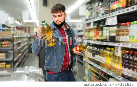 Ordinary bearded man looking for vegetable oil 64351633