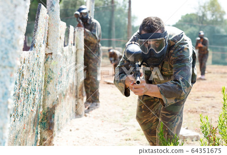 Paintball player aiming with gun Paintball player aiming with gun 64351675