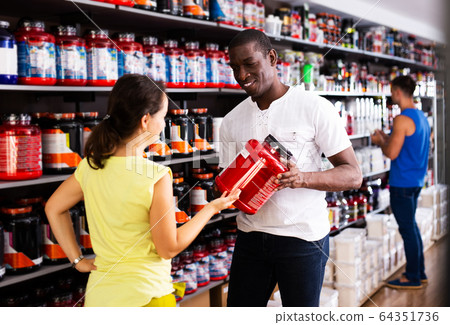 Woman choosing sports supplements in store 64351736