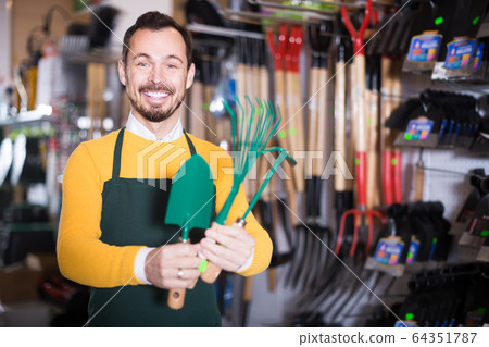 male seller showing assortment in garden equipment shop male seller showing assortment in garden equipment shop 64351787