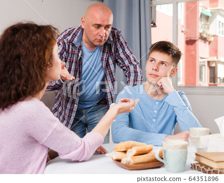 Teenager listening to reprimanding parents 64351896
