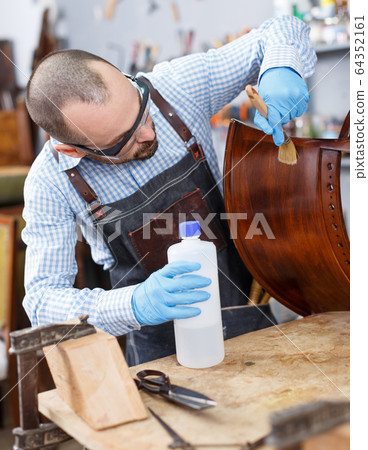 Workman varnishing antique armchair 64352161