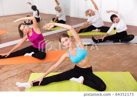 Women doing stretching exercises for yoga in the room Women doing stretching exercises for yoga in the room 64352173