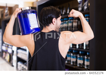 Athletic young man showing biceps Athletic young man showing biceps 64352174