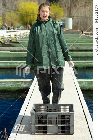 Female farm worker with crate of trout 64352177