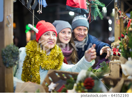 positive middle-aged married couple with a teenage daughter at Christmas market 64352193