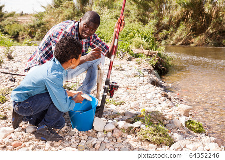 Man and boy holding fish on rod Man and boy holding fish on rod 64352246