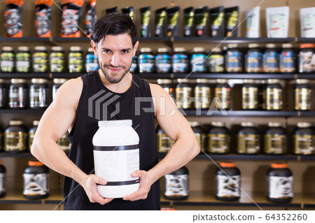 Attractive man holding sport nutrition products Attractive man holding sport nutrition products 64352260