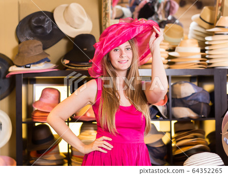 Positive blonde woman choose straw hat 64352265