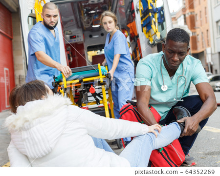 Ambulance team helping injured woman Ambulance team helping injured woman 64352269