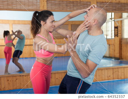 Woman is training with man on the self-defense course in gym Woman is training with man on the self-defense course in gym 64352337