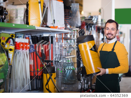 professional male seller showing assortment in garden equipment shop 64352369