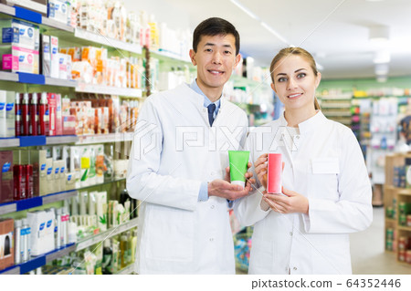 Portrait of two pharmacists posing with medicine in apothecary Portrait of two pharmacists posing with medicine in apothecary 64352446