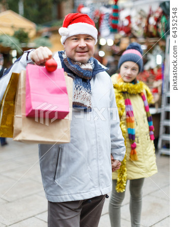 Smiling man in Santa hat with bags Smiling man in Santa hat with bags 64352548