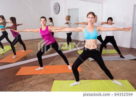 Women doing stretching exercises for yoga in the room Women doing stretching exercises for yoga in the room 64352594