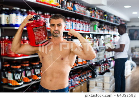 male standing with cans of sports nutrition 64352598
