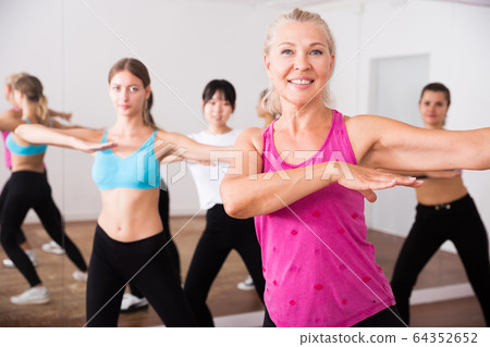 Group of active smiling people dancing together in dance studio 64352652