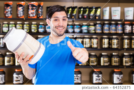 Cheerful sport man holding thumb up in store Cheerful sport man holding thumb up in store 64352875
