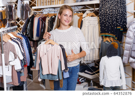 Girl holding and demonstrating baby clothes Girl holding and demonstrating baby clothes 64352876