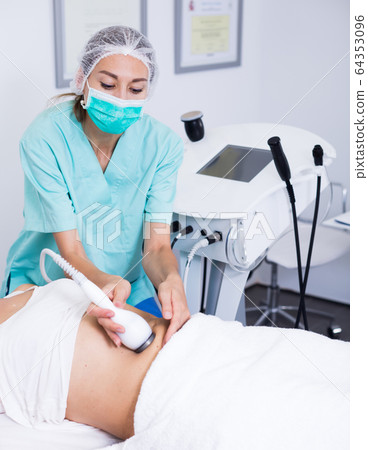 Professional cosmetician performing cryolipolyse Professional cosmetician performing cryolipolyse 64353096