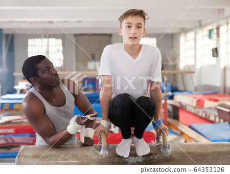 Ordinary African male coach helping teenage boy Ordinary African male coach helping teenage boy 64353126