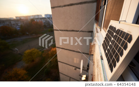 Solar panel on the window of a high-rise residential building, urban blurred background Solar panel on the window of a high-rise residential building, urban blurred background 64354148