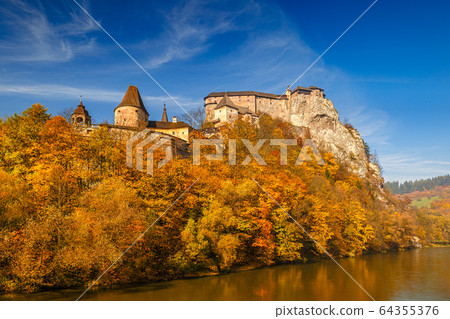 The medieval Orava Castle over a river at autumn. 64355376
