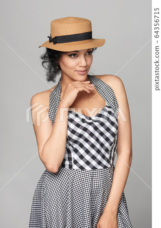 Woman in chequered summer dress looking out of frame smiling 64356715