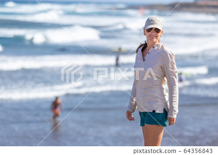 Young woman enjoying ocean view at windy beach. Young woman enjoying ocean view at windy beach. 64356843