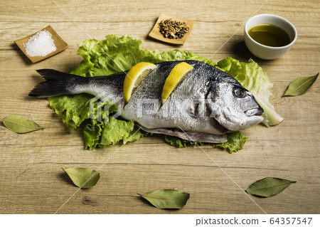 Dorada fresh fish on lettuce leaves next to some Dorada fresh fish on lettuce leaves next to some 64357547