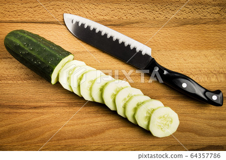 Whole and cut green cucumbers next to a knife 64357786