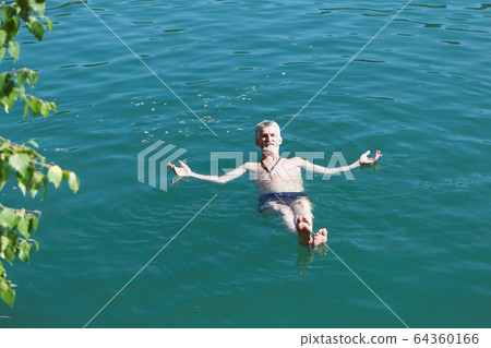 Man lying motionless on his back on the water 64360166