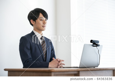 Image of a young man heading for a laptop with a webcam set for job hunting and web interview Image of a young man heading for a laptop with a webcam set for job hunting and web interview 64363836